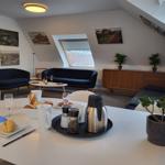 Wohnbereich mit Schlafsofa, Couch und Essplatz. Dachfenster, Bilder und Pflanzen.