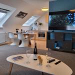 Wohnzimmer mit TV, Esstisch und Küchenbereich unter Dachschrägen.