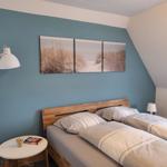 Schlafzimmer mit Doppelbett, Wandbild und Stehlampe.