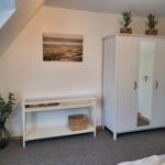 Schlafzimmer mit Kleiderschrank, Konsole und Pflanzen an der Wand.