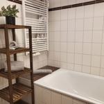 Badezimmer mit Badewanne, Holzregal und Heizkörper an der Wand.