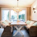 Essbereich mit wicker Sitzgruppe, Holztisch und Blick auf Garten.