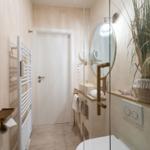 Bad mit Dusche, Waschtisch und Heizung. Große Pflanze auf der Arbeitsfläche.