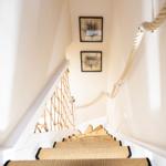 Treppe mit Seilgeländer und Teppichstufen, Wandbilder mit Bäumen