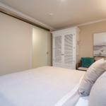 Schlafzimmer mit Bett, Kleiderschrank und Wandbild. Schlupftür und Hängeregler sind sichtbar.