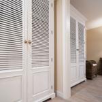 Zimmer mit weißen Schiebetüren, Wickerstuhl und Wandlampe