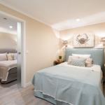 Schlafzimmer mit Bett, Wandbild und Nachttischen. Durchgang zu weiterem Schlafzimmer.