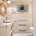 Badezimmer mit Waschbecken, Spiegel, Heizkörper und Toilette.