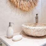 Waschbecken aus Stein mit Seifenspender und Handtuchhalter.