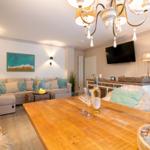 Wohn- und Essbereich mit Holztisch, Sofa und Fernseher an der Wand.