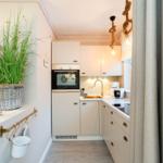 Küche mit weißen Schränken, Edelstahlspüle und Seilbeleuchtung.