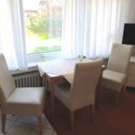 Esszimmer mit Tisch, vier Stühlen, Fernseher und Fenster mit Blick auf Garten.