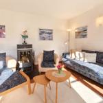 Wohnzimmer mit Sofa, Sessel und Kamin. Wandbilder und Holztisch.