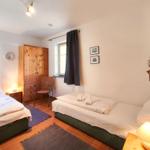 Zwei Betten, Holzschrank, Fenster mit Vorhang, Lampen und Wanddekoration.