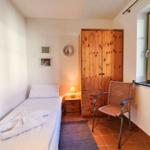 Ein Schlafzimmer mit einem Bett, einem Holzschrank, einem Stuhl und einem Fenster.