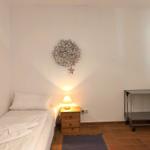 Ein Schlafzimmer mit Einzelbett, Nachttisch, Lampe und Wanddekoration.