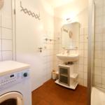 Badezimmer mit Waschmaschine, Dusche und Waschbecken