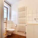 Badezimmer mit Dusche, WC und Heizkörper an der Wand.