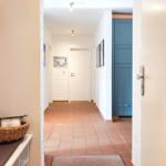 Flur mit Terrakottboden, blauer Schrank und Wandbildern