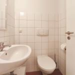 Badezimmer mit Waschbecken, Toilette und Spiegel an der Wand.