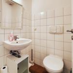 Badezimmer mit Waschbecken, Spiegel, Toilette und Toilettenpapier