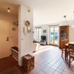 Eingangsbereich mit Wohn- und Essbereich, Holztisch, Stühle und TV.