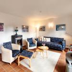 Wohnzimmer mit Sofa, zwei Sesseln, Kamin und Fernseher.