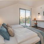 Schlafzimmer mit Doppelbett, Balkon und TV. Holzboden und moderne Beleuchtung.