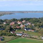 Luftbild eines Dorfes am Wasser mit Häusern und Grünflächen.
