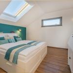 Schlafzimmer mit Dachschrägen, Dachfenster, Bett und Kleiderschrank.
