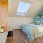 Schlafzimmer mit Dachschräge, Dachfenster, Bett und Holzboden.