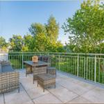 Terrasse mit Sitzgruppe und Tisch. Blick auf grüne Bäume und Garten.