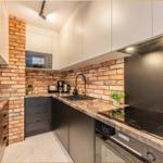 Küche mit Backsteinwand, Edelstahlspüle und Kochfeld