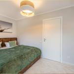 Schlafzimmer mit Bett, Wandbild und Deckenleuchte.