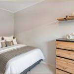 Schlafzimmer mit Bett, Kleiderschrank und Regal an der Wand.