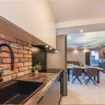 Küche mit Backsteinwand und Essbereich mit Tisch und Stühlen.