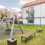 Hinter dem Haus befindet sich ein Spielplatz mit Schaukel und Bänken auf einer Wiese.