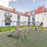 Hinterhof mit Spielplatz, Grünfläche und modernem Gebäude mit Balkonen.