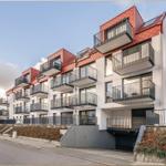 Moderne Wohnung mit Balkon und rotem Dach in ruhiger Wohngegend.