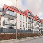Moderne Wohnung mit Balkon und rotem Dach in ruhiger Straße.