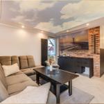 Wohnzimmer mit Sofa, Couchtisch und Fernseher an Backsteinwand. Decke mit Wolkenmotiv.