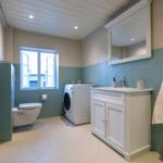 Badezimmer mit Waschmaschine, Toilette und Spiegelschrank.