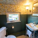 Badezimmer mit Zimtbaumtapete, grünen Fliesen und weißem Waschbecken.