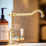 Edler Wasserhahn mit Drehkurbel und Seifenspender auf Küchenarbeitsfläche.