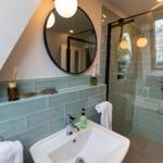 Badezimmer mit Waschbecken, Spiegel und Dusche mit Glaswand.