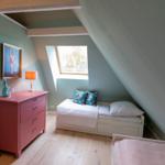 Schlafzimmer mit Dachschrägen, Fenster, Bett und Schrank.