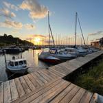 Hafen mit Booten und Holzsteg bei Sonnenuntergang.