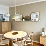 Runder Tisch mit vier Stühlen, Wandregal mit Bildern und Lampe.