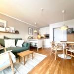 Wohnzimmer mit Sofa, Esstisch und Küche im offenen Raum. Holzfußboden und weiße Möbel.