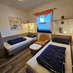 Zwei Einzelbetten, ein Sessel und ein Fenster mit Vorhängen.